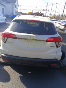 A white SUV with its rear wheels secured on a tow dolly, being prepared for transport by Buffalo Towing Services in Buffalo, NY.