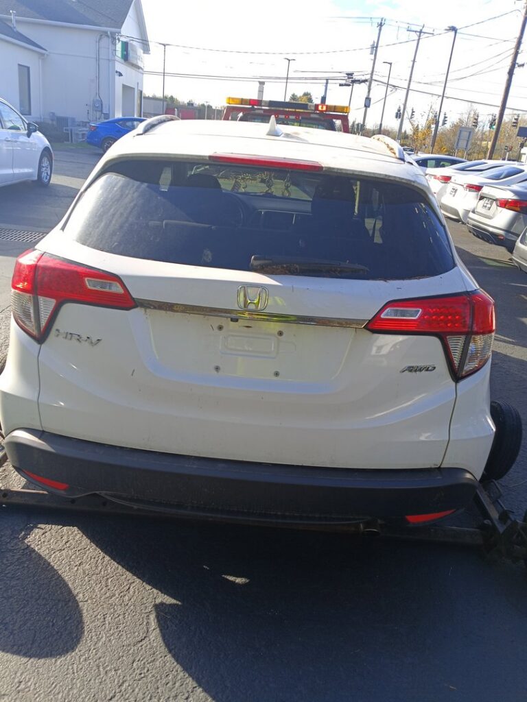 A white SUV with its rear wheels secured on a tow dolly, being prepared for transport by Buffalo Towing Services in Buffalo, NY.
