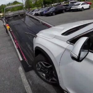 A white SUV partially loaded onto a flatbed tow truck for a towing service by Fort Benning Towing in Columbus, GA