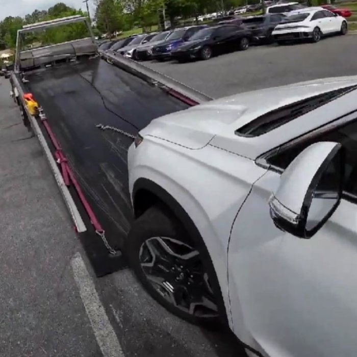 A white SUV partially loaded onto a flatbed tow truck for a towing service by Fort Benning Towing in Columbus, GA