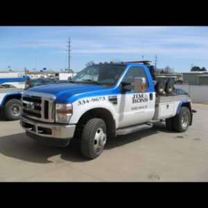 A white SUV being towed with specialized low-clearance equipment by Jim & Ron's Service Inc. in Sioux Falls, SD.