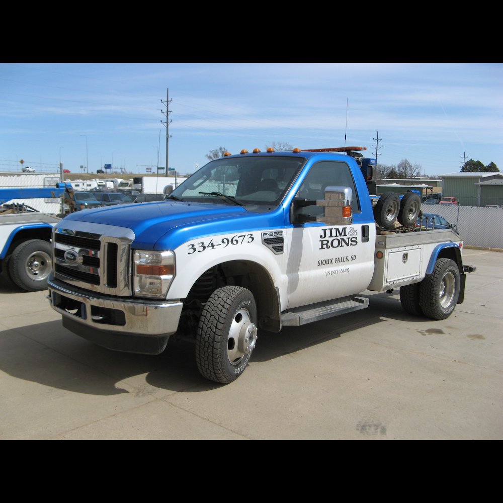 A white SUV being towed with specialized low-clearance equipment by Jim & Ron's Service Inc. in Sioux Falls, SD.