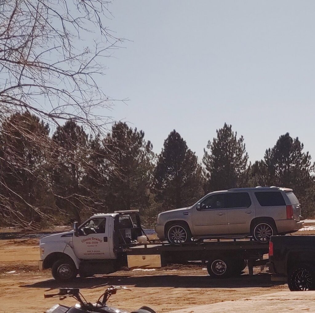 A white SUV being safely transported on a Classic Towing llc flatbed truck in Greeley, CO.