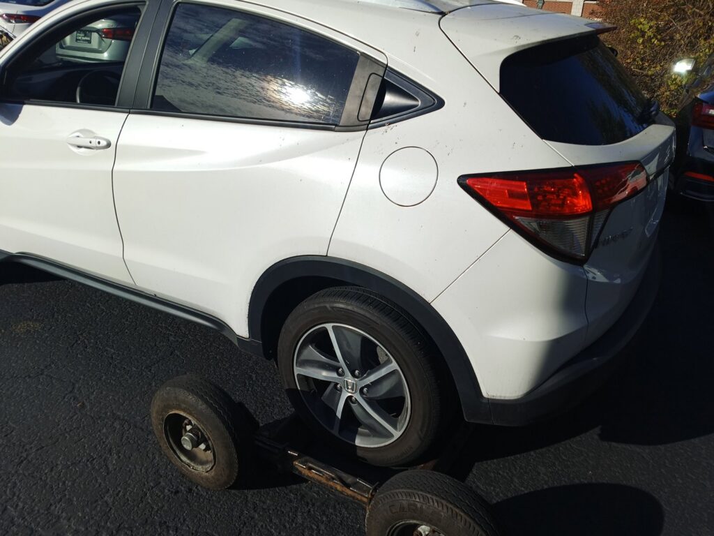 A white SUV with a wheel dolly attached to its rear wheel, ready for transport by Buffalo Towing Services in Buffalo, NY.