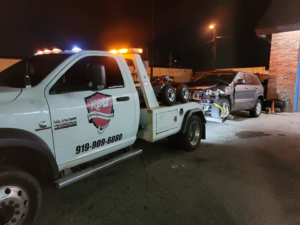 A white tow truck from RDU Towing & Recovery Services towing a damaged Jeep Grand Cherokee in Raleigh, NC.