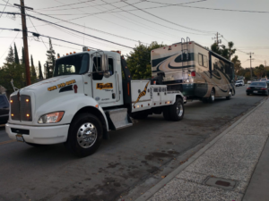 A white Aguilar Towing truck providing heavy-duty towing for a large RV in San Jose, CA