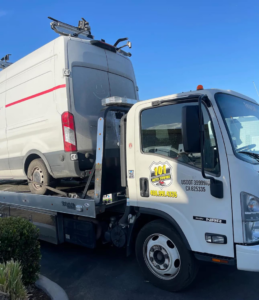 A white commercial van being towed on a flatbed truck by 101 auto towing inc in San Jose, CA.