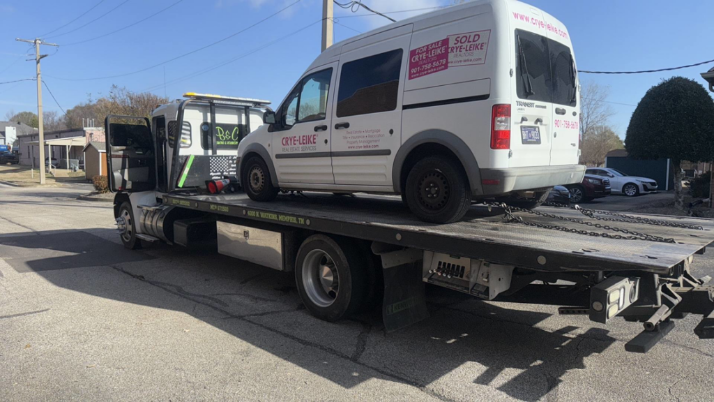 A white commercial van being transported on a rollback tow truck by A&A Trucking in Memphis, TN.