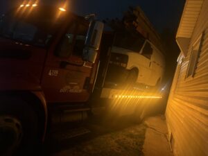 A white van being towed on a flatbed tow truck at night by Tow & go in Louisville, KY.