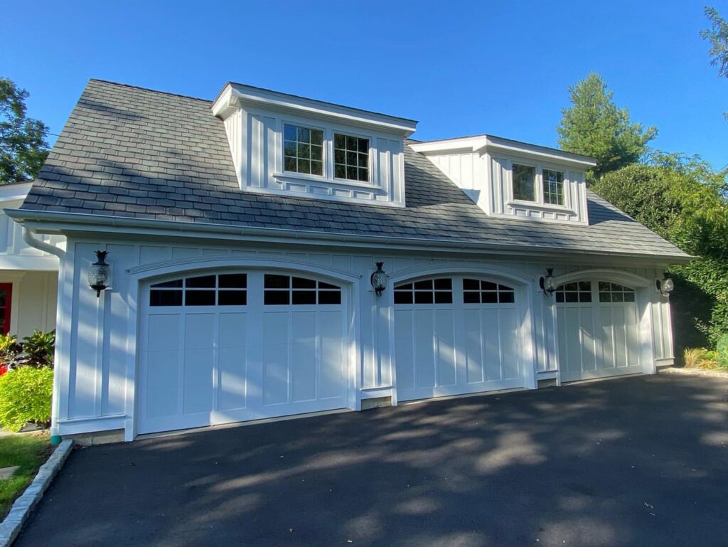 A garage with elegant white vertical siding and matching garage doors by Ideal Siding Winston-Salem, NC.
