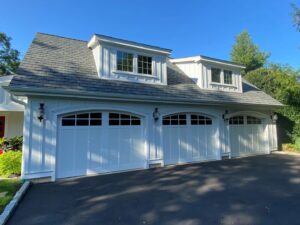 A garage with elegant white vertical siding and matching garage doors by Ideal Siding Winston-Salem, NC.