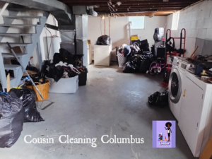 A wide view of a basement with a cleared floor and numerous trash bags, showcasing cleaning progress by Cousin Cleaning Columbus, OH.