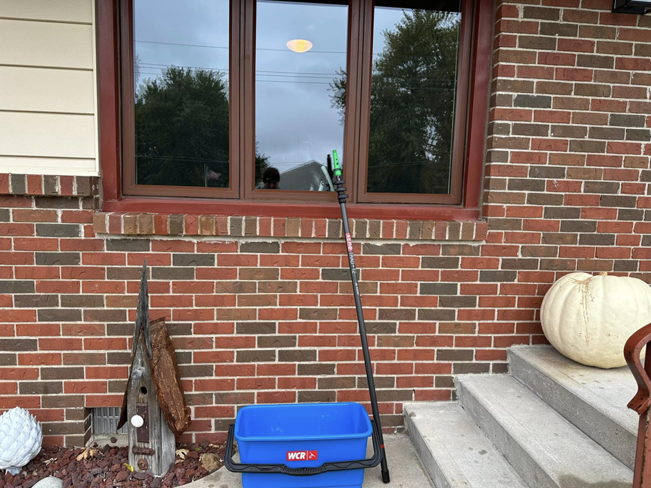 A window cleaning bucket and pole placed outside a residential house, ready for service by Rocket Window Cleaning in Lincoln, NE.