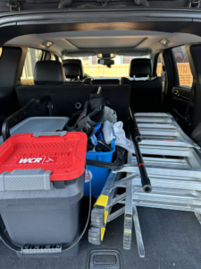 Window cleaning equipment, including buckets, squeegees, and ladders, loaded in an SUV for Rocket Window Cleaning in Lincoln, NE.