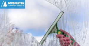 A hand using a squeegee to clean a window, showing suds, by Intermountain Cleaning Service in Yakima, WA
