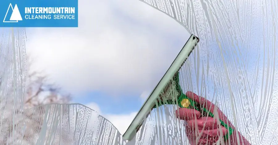 A hand using a squeegee to clean a window, showing suds, by Intermountain Cleaning Service in Yakima, WA