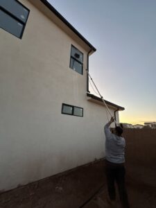 A professional cleaning windows of a house with a long pole by Farki Pressure Washer LLC in Mesquite, NV