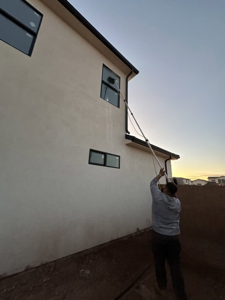 A professional cleaning windows of a house with a long pole by Farki Pressure Washer LLC in Mesquite, NV