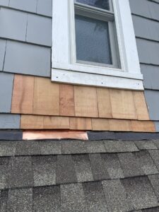 Installation of new cedar shingles and copper flashing below a window to prevent water damage by Peach3 Group in New Rochelle, NY.