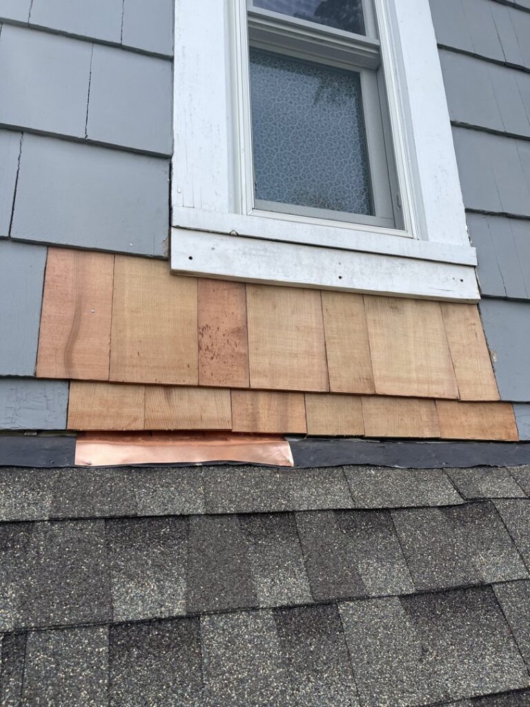 Installation of new cedar shingles and copper flashing below a window to prevent water damage by Peach3 Group in New Rochelle, NY.