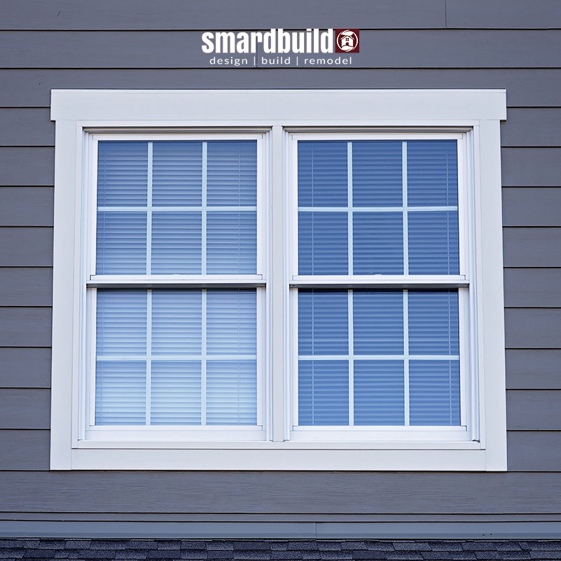 A window framed by gray siding, showcasing work by SmardBuild Siding and Exteriors in Naperville, IL