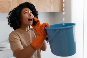 A woman catching water from a ceiling leak with a bucket, indicating a water damage emergency in Tulalip, WA.