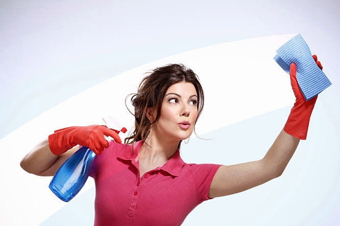 A woman in cleaning gloves holding a spray bottle and cloth, actively cleaning a surface for Fabulous Cleaning Services in Charlotte, NC.