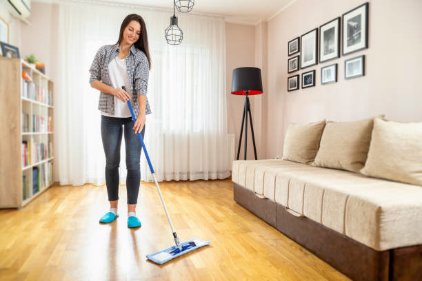 A woman mopping a hardwood floor in a living room, demonstrating floor cleaning services by Cascade Fresh Cleaning Services in Grand Rapids, MI.