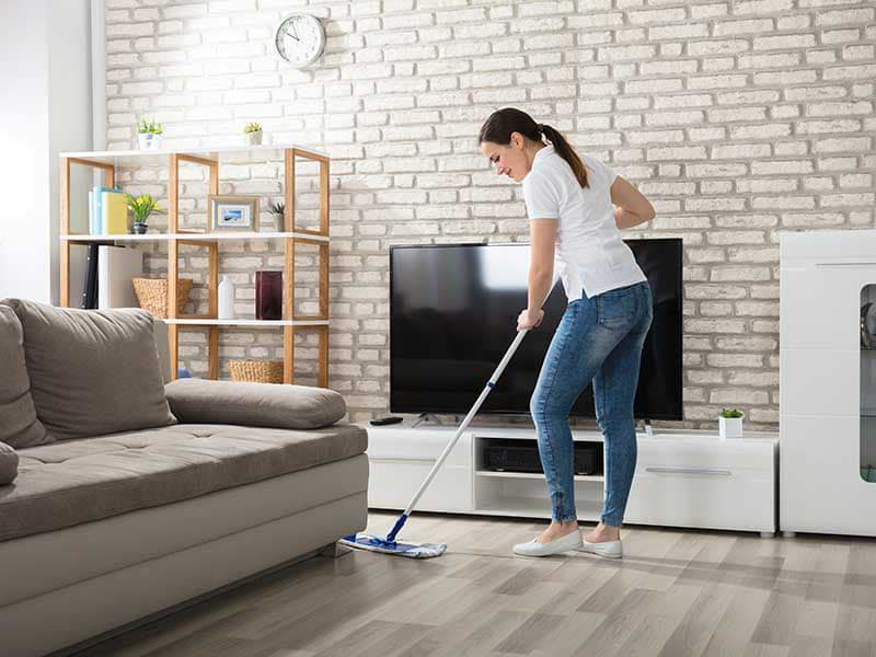 A woman mopping a living room floor, providing house cleaning services for Spit Spot Cleaning Services in Chandler, AZ.