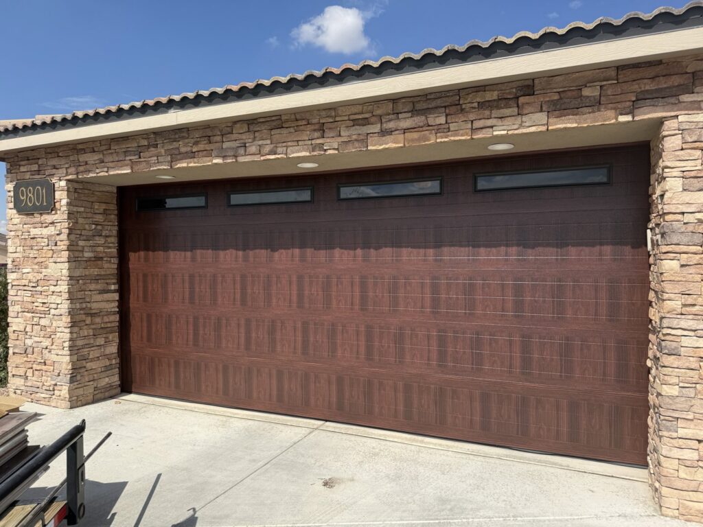 A residential home with a stylish brown wood-grain garage door, installed by Quality-Brand Garage Doors in Rio Rancho, NM.
