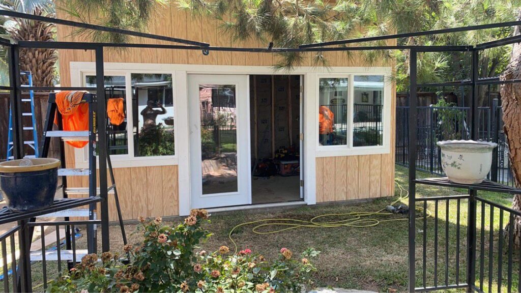 A small shed-like structure with new wood panel siding and white-framed windows and doors by Bushco Contracting LLC in Fresno, CA.