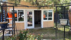 A small shed-like structure with new wood panel siding and white-framed windows and doors by Bushco Contracting LLC in Fresno, CA.