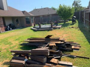 A pile of wooden planks and posts from a dismantled deck, ready for removal by Vaquero Demolition in Lewisville, TX.