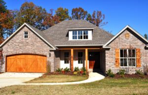 A beautiful wooden garage door installed on a brick house by Coney's Garage Doors in Conway, AR.