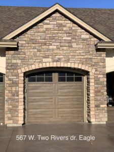 Single wooden-look garage door with an elegant arched stone facade installed by Garage Door Store Boise, ID.