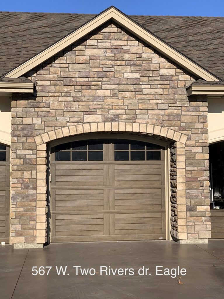 Single wooden-look garage door with an elegant arched stone facade installed by Garage Door Store Boise, ID.