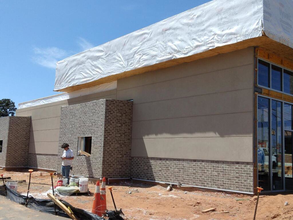 A worker applying stucco siding to a commercial building under construction by Eastern Stucco Restorations in Rock Hill, SC.
