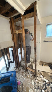 A worker performing demolition in a bathroom, removing damaged materials during water damage restoration in Syracuse, UT by Utah Disaster Specialists.