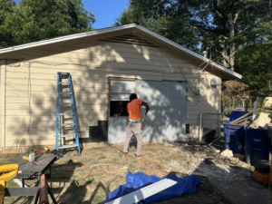 A worker breaking down an exterior wall section during demolition by Rayshawn's Home improvement & Construction work in Bossier City, LA.