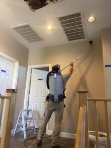 A worker from Western Skies Restoration cleaning a ceiling after damage in a home in Gilbert, AZ.