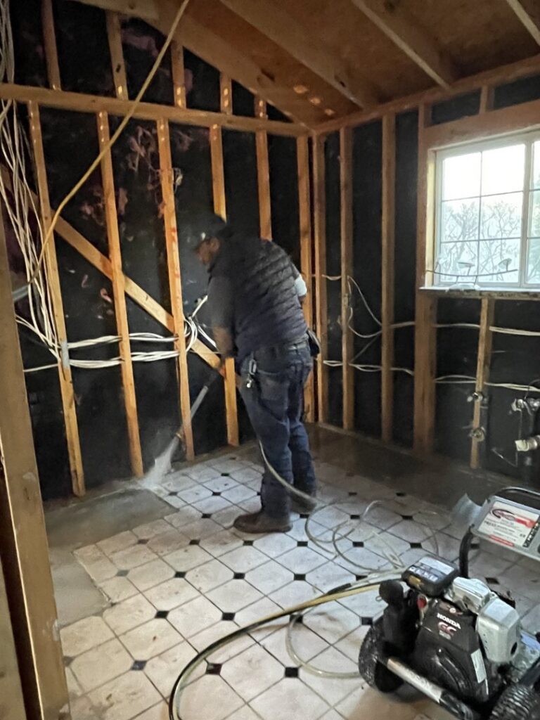Worker cleaning a stripped subfloor during water damage remediation by 1st Response Emergency Repairs, LLC in Scott, LA.