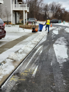 A worker using a snow blower to clear a sidewalk, providing snow removal services by American Snow Plowing Services in Rockville, MD.