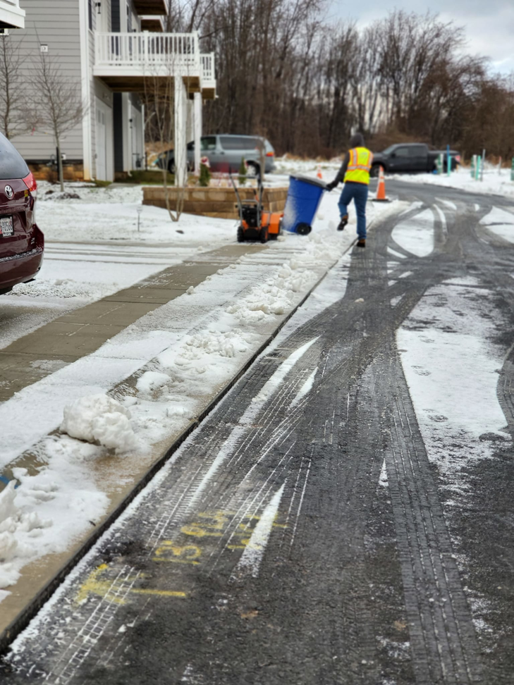 A worker using a snow blower to clear a sidewalk, providing snow removal services by American Snow Plowing Services in Rockville, MD.