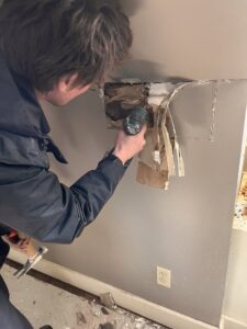 A Paul Davis Restoration of Greater Portland, ME worker demolishing a damaged wall section during restoration.