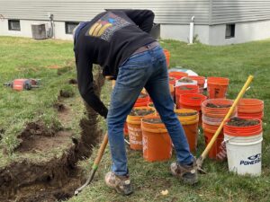 A worker from EFFECTIVE WATERPROOFING digging a drainage trench in Worcester, MA.