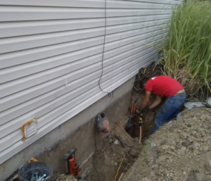 A worker digging a trench for foundation waterproofing or repair by Fort Wayne Foundation Repair Experts in Fort Wayne, IN.