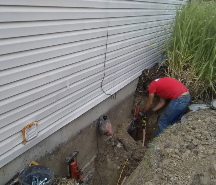 A worker digging a trench for foundation waterproofing or repair by Fort Wayne Foundation Repair Experts in Fort Wayne, IN.