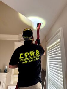 A worker from Carolina Pro Restoration LLC in Fort Mill, SC, drying a ceiling cavity during water damage restoration.