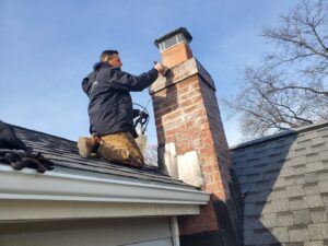 A worker on a roof inspecting a chimney for potential leaks and water damage at Barbera Home Improvement in Parma, OH.