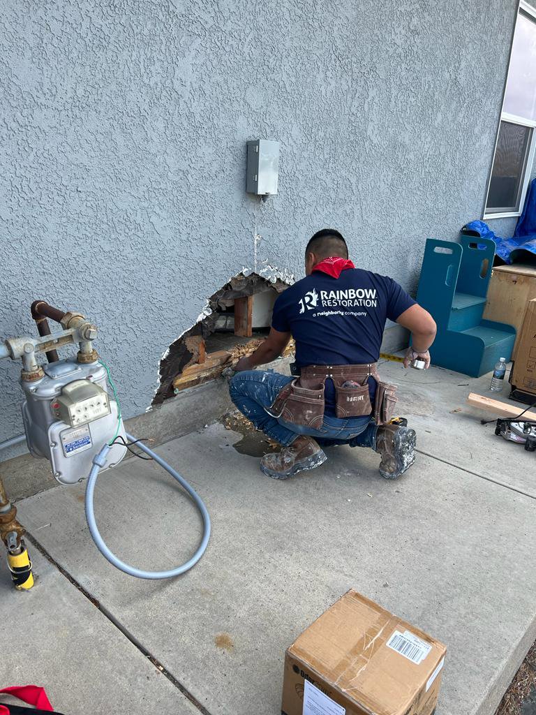 A Rainbow Restoration of Meridian worker inspecting a damaged exterior wall, likely for water damage or leaks, in Meridian, ID.